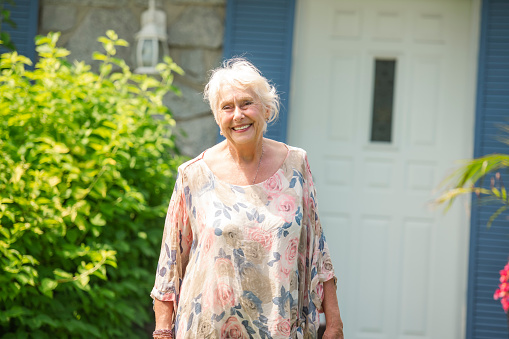 A Portrait of senior woman in front of her house