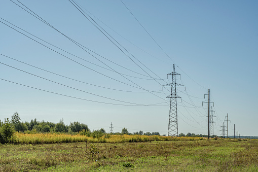 Power line towers. Out-of-town power supply system. Energy infrastructure in the fields in the countryside.