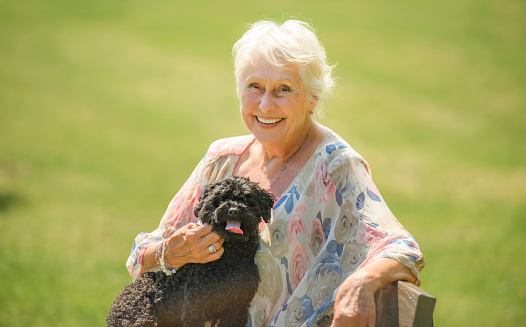 A Senior Woman with Pet Dog outside in nature with poodle