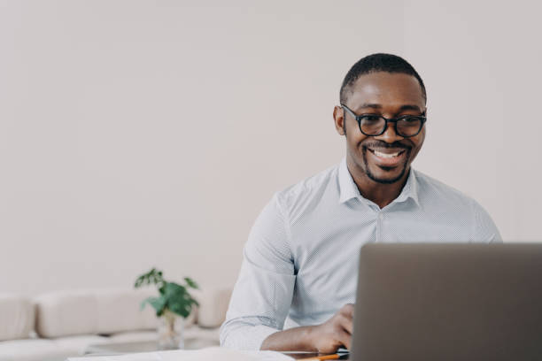 istock Smiling african american man software developer working online at laptop reads email with good news 1438145516