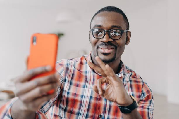 istock African american man shows ok approving gesture by hand, holding phone, communicates by video call 1438145536