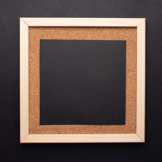 Photo of Cork note board with wooden frame, black square sheet for text or messenge on black background.