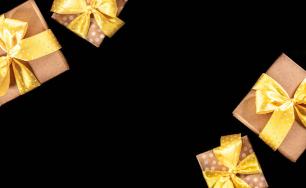 istock Gift boxes with yellow polka dot ribbons and bows on black backdrop. Top view. Copy space. 1438147732