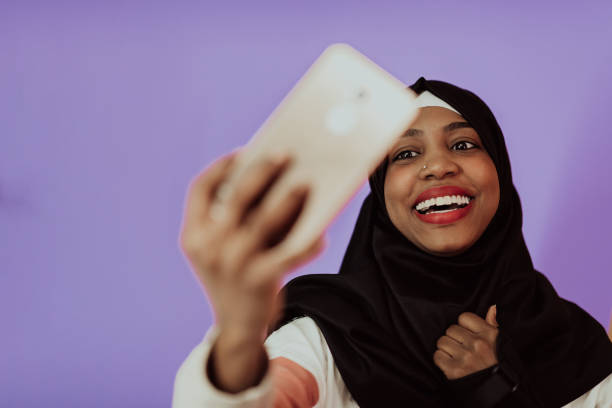 istock Afro woman using a smartphone in front of a pink background 1438147806