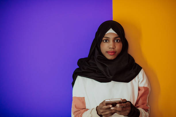istock Afro woman using a smartphone in front of a pink background 1438149130