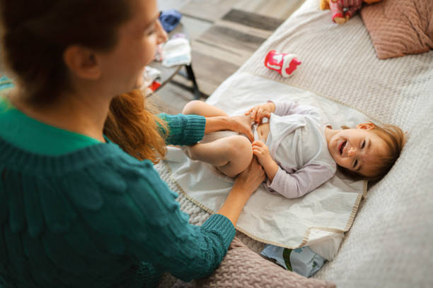 Happy loving mother changing her little daughters diapers