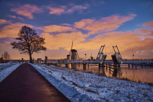 A windmill in a Dutch winter landscape at dawn.