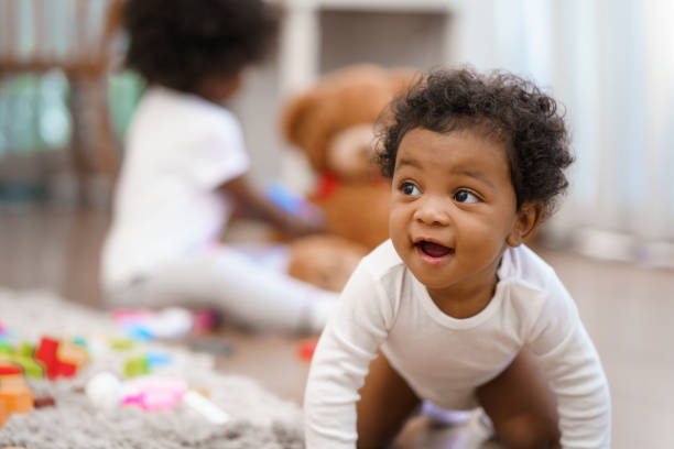 feliz afroamericano pequeño bebé gateando y buscando algo que aprender - niños bebés fotografías e imágenes de stock