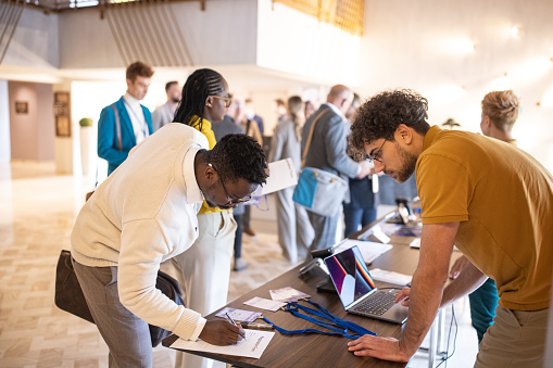 A group of business conference participants registering for a conference in the lobby of a luxury hotel