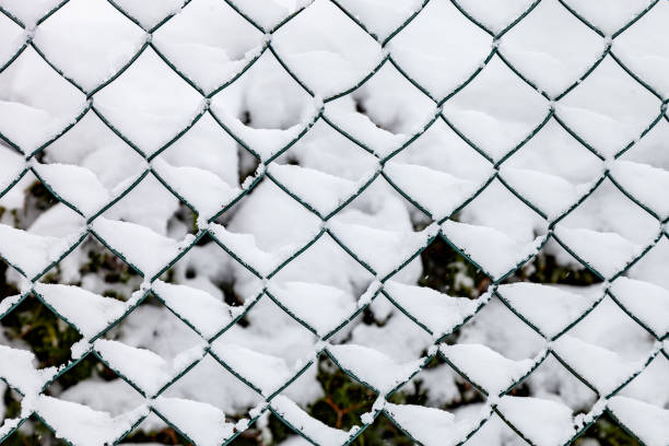 Chain link fence with snow background in wintertime close up