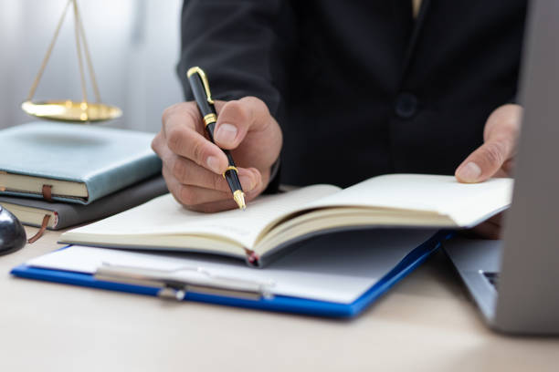 istock Legal counsel is writing a note on a notepad while working in a lawyer's office. 1438154455