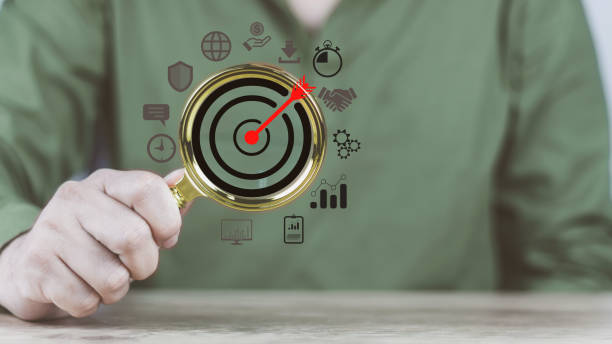 istock information technology business concept man hand holding a magnifying glass showing target icon Business planning materials to achieve the set goals 1438156190