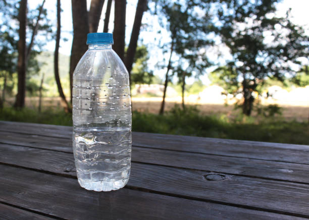 bouteille d’eau en plastique vide sur une table en bois dans la nature - transparent ideas lid glass photos et images de collection