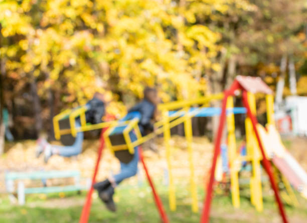 Defocused image of bright yellow foliage on playground on sunny autumn day in park
