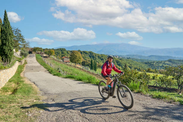 nice senior woman riding her electric mountain bike in Tuscany, Italy stock photo