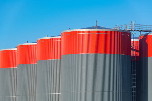 Steel panels, spiral staircase and railing of a weathered oil and gas fuel storage tank against the sky.  Belfast, Northern Ireland.