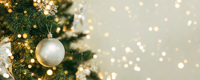 Seamless panoramic banner with Christmas composition of Christmas festive baubles and branches of fir tree on a beige background. Defocused lights on background. Copy space.