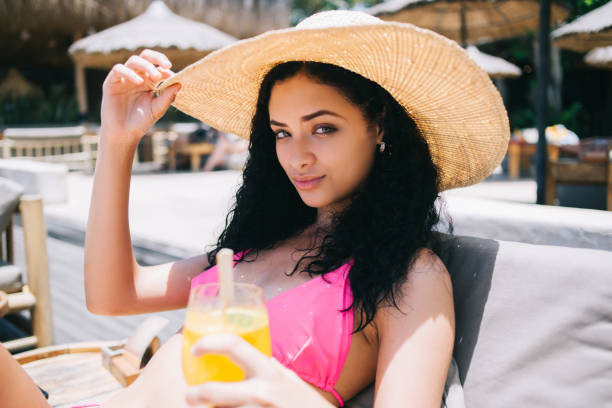 istock Beautiful young lady in bikini with juice lying on sunbed 1438160501