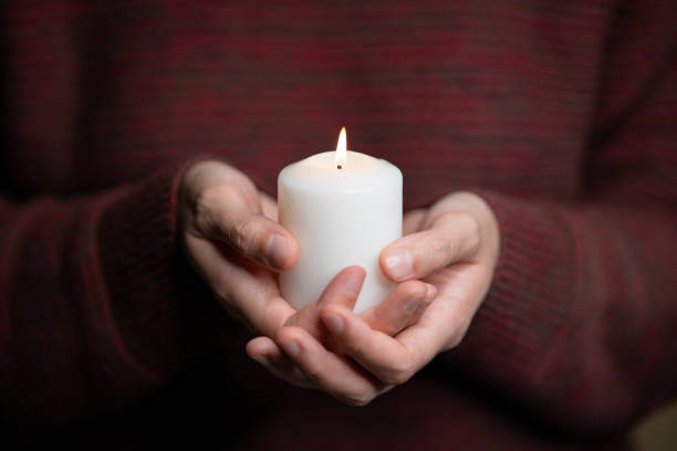 istock Man holding a candle in front of his chest 1438166593