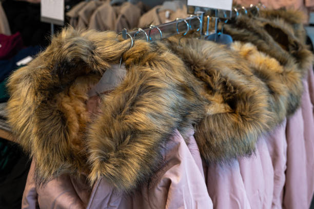 istock Winter jackets with fur collars hanging on plastic hangers in a store. 1438167993