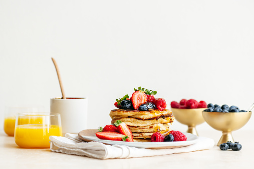 A stack of sourdough pancakes with berries and orange juice