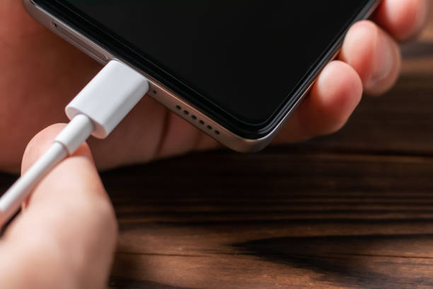 istock Man hands plugging a charger in a smart phone. Man using smartphone with powerbank. 1438169393