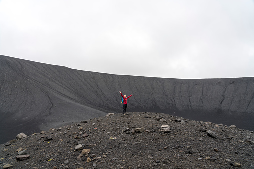 with arms raised.  Hverfjall, is one of the best preserved circular volcanic craters in the world and it is possible to walk around and inside it.