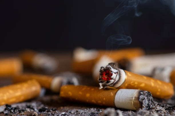 istock Cigarette butt on wooden table with black background 1438177468