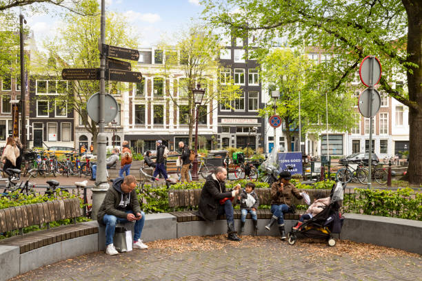 People on a bench at a playground in the Jordaan near the Prinsengracht in Amsterdam. Amsterdam, Netherlands, May 23, 2021; People on a bench at a playground in the Jordaan near the Prinsengracht in Amsterdam. jordaan amsterdam stock pictures, royalty-free photos & images