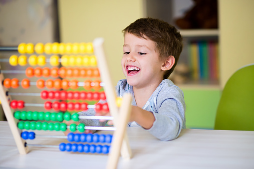 A joyful Caucasian toddler boy learning to count using the abacus