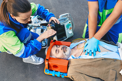 First aid, ambulance. Paramedics provide first aid to injured man with medical equipment, give heart massage and CPR to patient to save his life