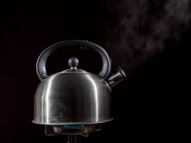 istock Kettle on a gas tourist burner. Kettle on a burner on a dark background. 1438180435