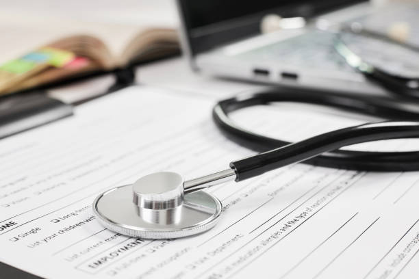 istock Phonendoscope or stethoscope with an Adult New Patient Questionnaire on notepad background and laptop 1438180515