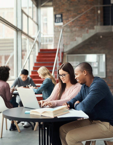 istock University, laptop and students study in library together for exam, test or project research. Education, learning and college people preparation for studying, application or assignment. 1438180708