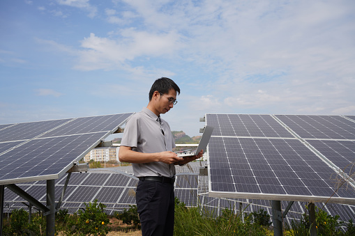 Engineer working with laptop in front of solar panels