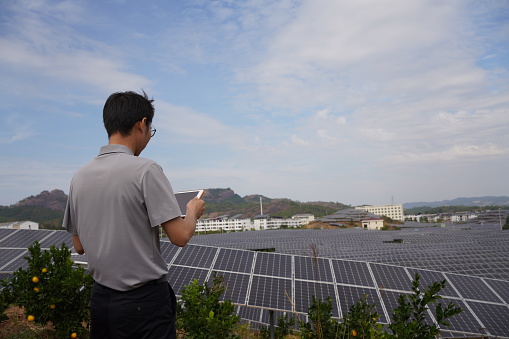 Engineer checking with tablet in front of solar panel