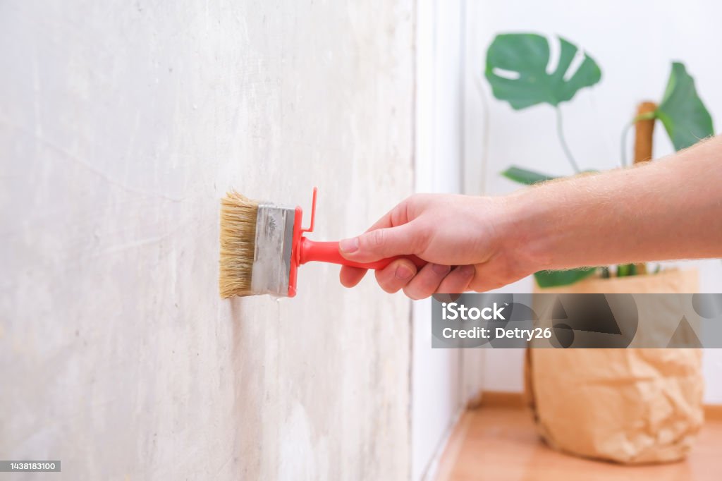 A Man Applies Wallpaper Glue With Brush For Wallpapering Repair Of