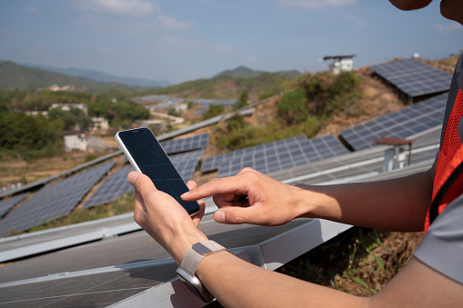 Engineer using mobile phone in front of solar panels