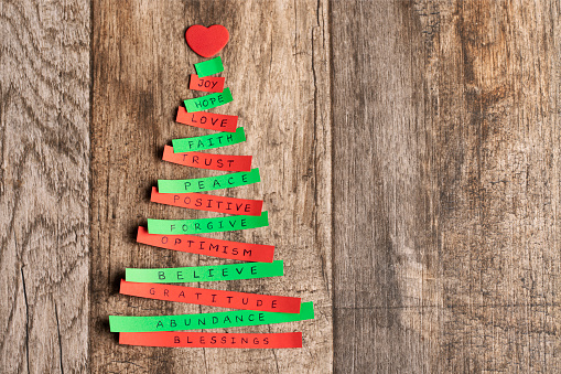 Abstract Christmas tree made of green and red paper with words,  on wooden background
