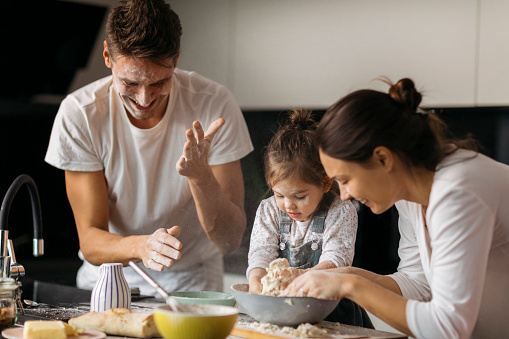 Cheerful family preparing lunch in the modern kitchen with young happy kid