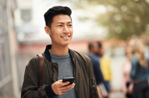 istock Asian man, phone and student with smile for vision, idea or thinking in communication with 5G connection outside. Happy academic male in thought for conversation, texting or chatting on smartphone 1438185788