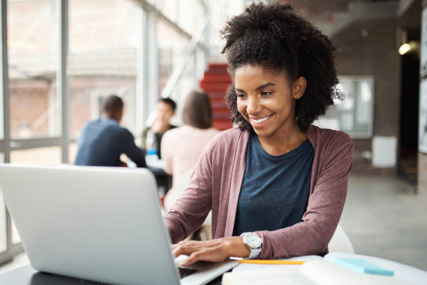 istock Black girl, college student and study, education and laptop for research on writing assignment or studying for class. Young, smile and university, search on internet and ideas in notebook with tech. 1438186576