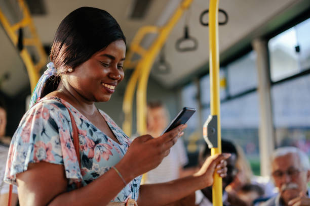 African american woman looking at smarpthone in public bus stock photo
