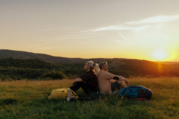 istock Traveler couple sitting on meadow while taking a break 1438189187