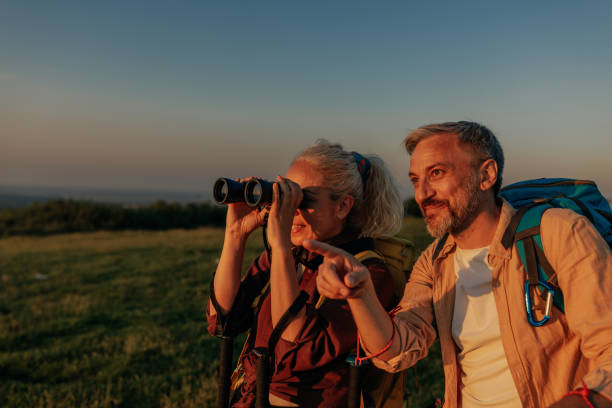 mujer mirando con binoculares hombre apuntando dirección en montaña - couple walking old middle fotografías e imágenes de stock