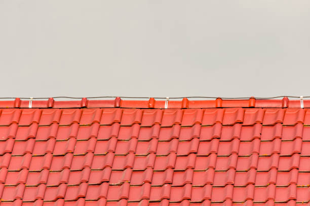 New red tiles on a home against grey background. Roofing or construction concept
