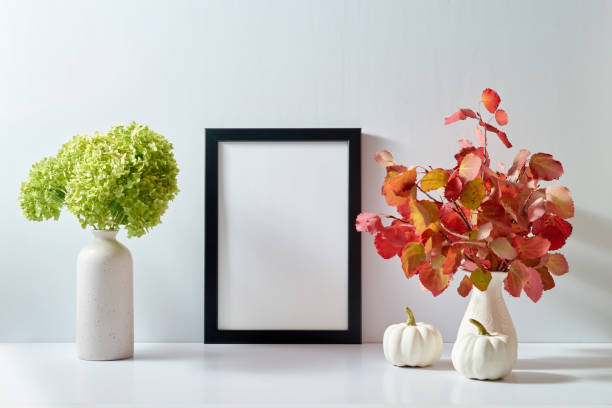 istock Mockup with a black frame and colorful autumn leaves in a vase on a light background. Empty poster frame mockup for presentation design, text, lettering 1438196338