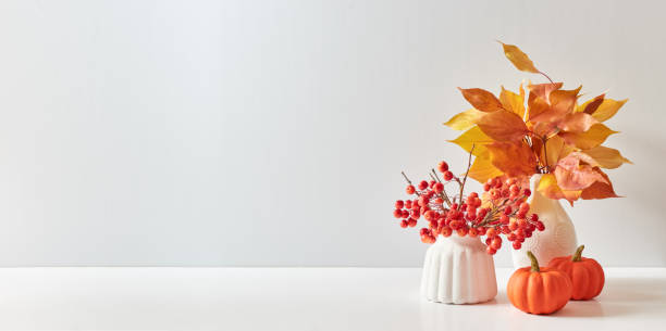 istock Home interior with decor elements. Colorful autumn leaves in a vase on a light background. Mock up for displaying works 1438196339