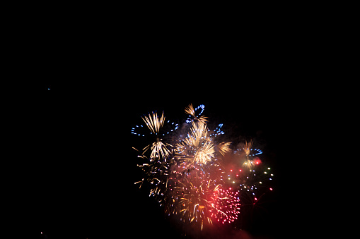 Colorful bright fireworks isolated on a black background with empty space for text in the middle.