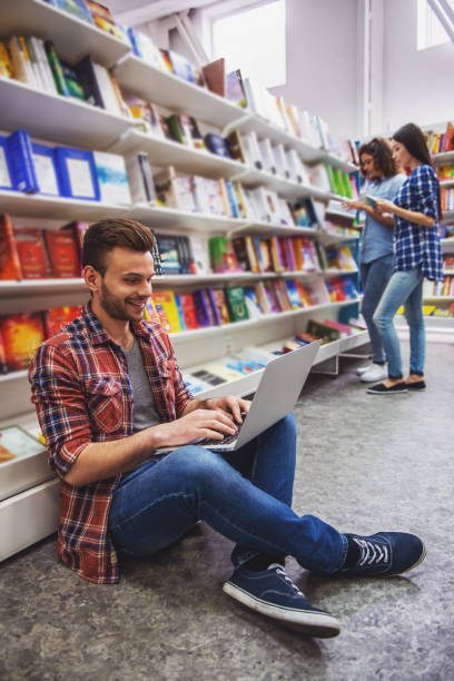 istock Students with gadget at the bookshop 1438198981